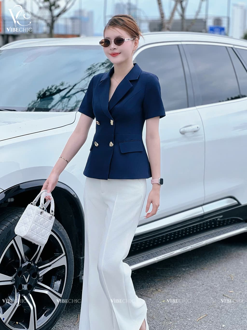 Người mẫu diện một bộ trang phục thanh lịch và hiện đại, kết hợp hài hòa giữa áo blazer và quần ống rộng
